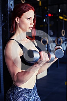 Happy determined woman working out with dumbbells at home