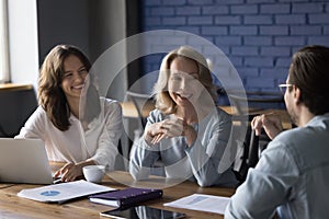 Happy different aged team of office coworkers meeting at table