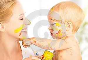 Happy dirty baby draws paints on her face of mother