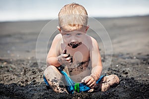 Happy dirty child play with sand on family beach vacation