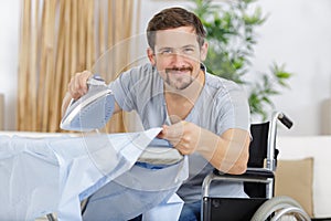 Happy disabled man ironing shirts at home