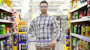 Happy disabled man in plaid shirt with amputated arm in shop smiles and looks at camera