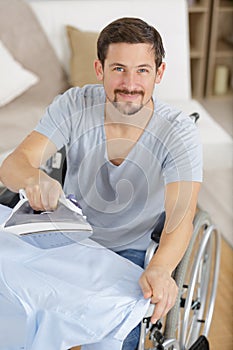 Happy disabled man on wheelchair ironing clothing