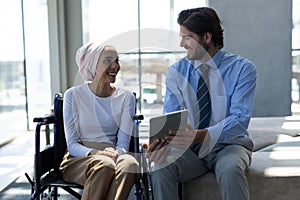 Happy disabled mixed-race female executive with Caucasian businessman discussing over digital tablet