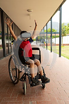 Happy disabled schoolboy using virtual reality headset in corridor