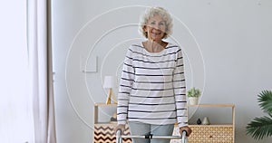 Happy disabled senior woman stand hold walker looking at camera