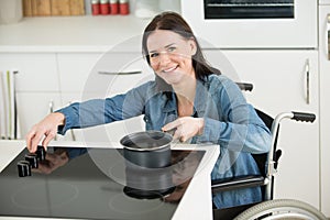 happy disabled woman in wheelchair cooking dinner