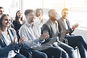 Happy diverse audience applauding at business seminar