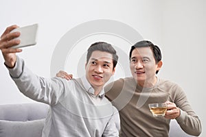 Happy diverse best friends making selfie on mobile phone at home