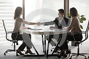 Happy diverse business partners handshaking at office meeting