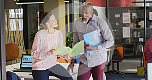 Happy diverse business people holding documents and discussing work at office