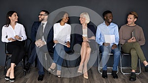 Happy diverse business people sitting in row, waiting for interview