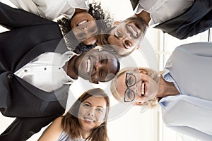 Happy diverse business team gathering in circle looking at camer