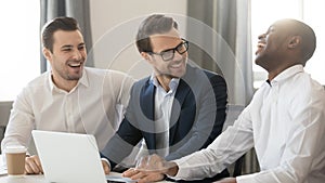 Happy diverse businessmen colleagues talking laughing at joke working together