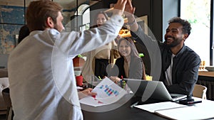 Happy diverse businessmen give high five during team corporate brainstorm, coworkers celebrate good successful teamwork