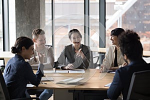 Happy diverse businesspeople laugh, brainstorm, discuss business ideas in office