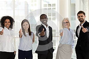 Happy diverse businesspeople standing looking at camera showing thumbs up