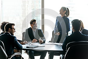 Happy diverse colleagues laugh brainstorming at meeting together