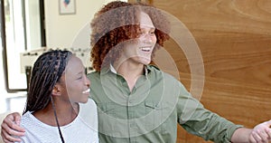 Happy diverse couple greeting friends at front door of home, slow motion