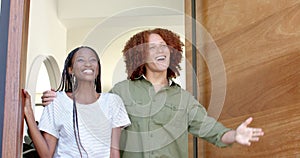 Happy diverse couple greeting male friend with wine at front door of home, slow motion