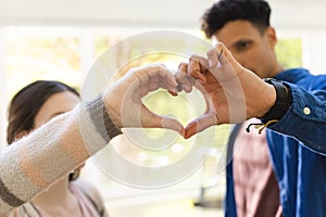 Happy diverse couple making a heart symbol with hands at home, copy space