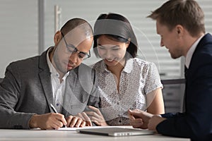 Happy diverse couple signing contract, making purchase deal