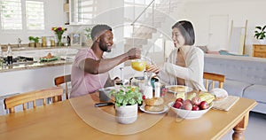 Happy diverse couple sitting at table and having breakfast