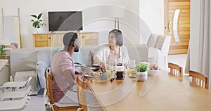 Happy diverse couple sitting at table and having breakfast