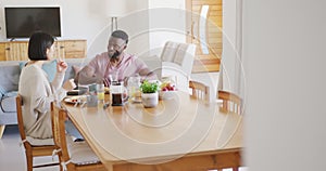 Happy diverse couple sitting at table and having breakfast