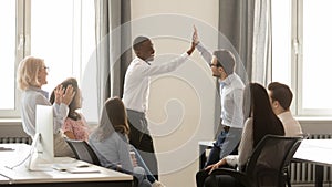 Happy diverse employees giving high five together celebrating shared win