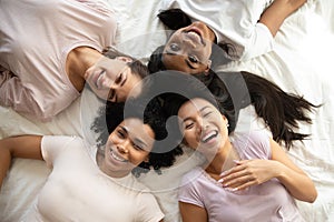 Happy diverse ethnicity young girls friends on bed, top view