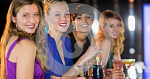 Happy diverse female friends smiling and enjoying drinks at bar