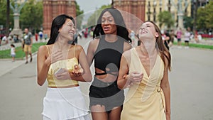 Happy diverse female friends tourists walking on street in city during travel trip
