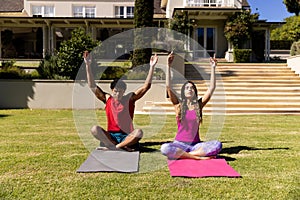 Happy diverse fit couple practicing yoga sitting in sunny garden