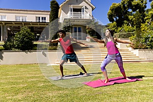 Happy diverse fit couple practicing yoga standing and stretching in sunny garden