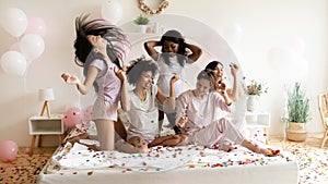 Happy diverse girls having fun, celebrating in bedroom with confetti