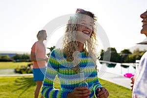 Happy diverse group of friends having party, drinking beer and talking in garden