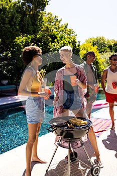 Happy diverse group of friends having pool party, barbecuing together in garden