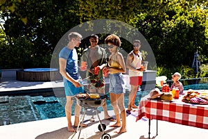 Happy diverse group of friends having pool party, barbecuing together in garden