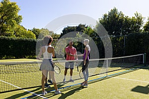 Happy diverse group of friends playing tennis, shaking hands at tennis court