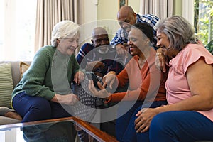 Happy diverse group of senior friends having video call and smiling in sunny living room