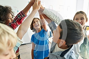 Happy diverse kids school students group giving high five together in classroom.