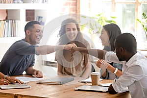 Happy diverse male colleagues students fist bumping at group meeting