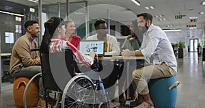 Happy diverse male and female business colleagues and disabled businesswoman talking in office
