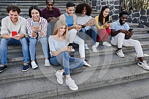 Happy diverse people using mobile phones outdoor in the city - Main focus on center girl face