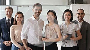 Happy diverse professional leaders looking at camera stand with employees