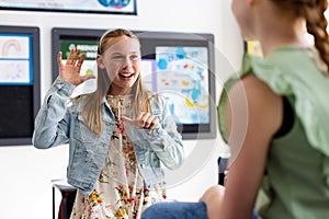 Happy diverse schoolchildren using sign language in school classroom