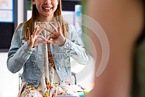 Happy diverse schoolchildren using sign language in school classroom