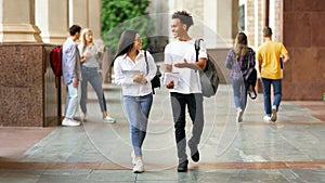 Happy diverse students walking in college campus