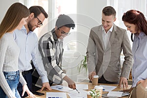 Happy diverse team brainstorm in office with papers on table